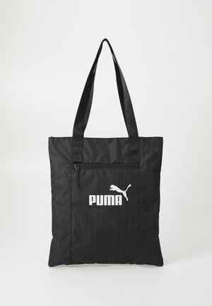 Schwarze Puma Tragetasche mit vorderer Reißverschlusstasche und doppelte Schultergurte vor schlichtem hellem Hintergrund.
