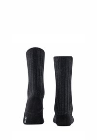 Schwarze Socken mit vertikalen Rippungen, die metallische Flecken für eine besondere Textur aufweisen. Der Bund ist elastisch, und ein Logo befindet sich an der Sohle.