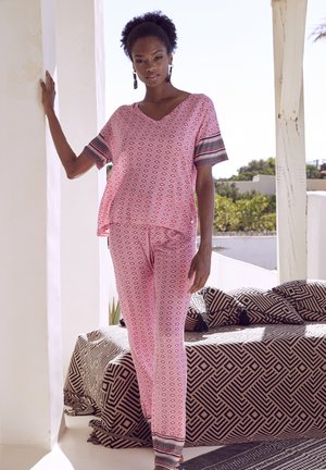Rosa gemusterte Bluse mit V-Ausschnitt und kurzen Ärmeln, kombiniert mit passenden Hosen, die ein Diamantmuster und kontrastierende gestreifte Abschlüsse aufweisen.