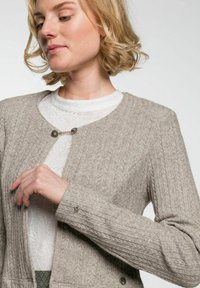 Hellbrauner Cardigan mit strukturierten Strickmustern, rundem Halsausschnitt, langen Ärmeln und einem dekorativen metallischen Verschlussdetail.