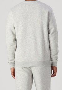 Felpa grigia in morbido misto cotone, con colletto a girocollo e polsini a costine, caratterizzata da un design texturizzato e a flocchi.