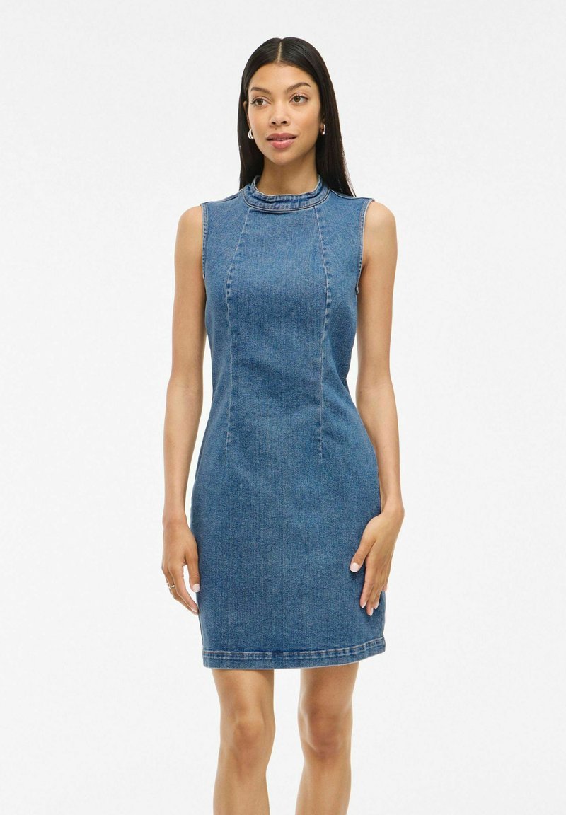 Robe en denim sans manches, avec un col montant, design ajusté, longueur mi-cuisse et coutures contrastées. Couleur bleu clair, texture lisse.