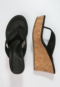 Černé kožené sandály na wedge podpatku s texturovaným páskem, korkovou podešví a plochým podpatkem. Disponují hladkým povrchem a minimálními ozdobami.