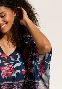 Blusa navy con stampa floreale, scollo a V, maniche morbide e un tessuto leggero e trasparente con accenti rosa e bianchi.