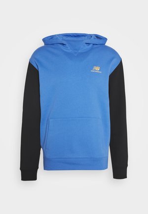 Blauer Kapuzenpullover mit schwarzen Ärmeln, ausgestattet mit einer Fronttasche und einem goldenen "New Balance"-Logo auf der Brust. Weiche Stoffstruktur.