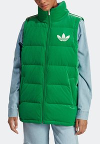 Grön vadderad väst med hög krage, med en vit Adidas-logga. Tillverkad av mjukt tyg, har sidofickor och dragkedjestängning.