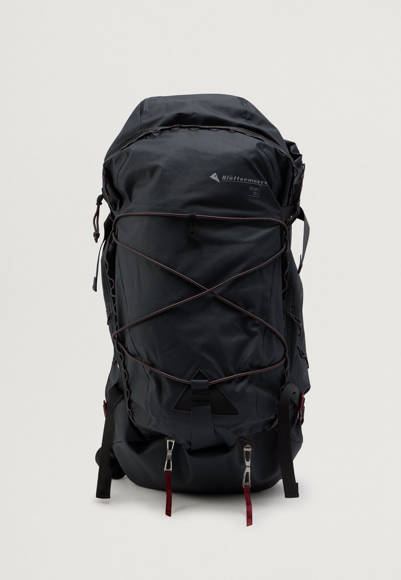 Črn nahrbtnik iz najlona s poenostavljenim dizajnom. Ima sistem bungee vrvic, nastavljive naramnice in kovinske dodatke.