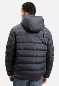 Puchowa kurtka w ciemnoszarym kolorze, wyposażona w kaptur, pikowany wzór i ściągacze przy mankietach. Materiał ma gładką teksturę z widocznymi liniami szwów.