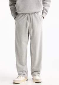 Hellgraue, locker sitzende Sweatpants mit elastischem Bund und Kordelzug, ausgestattet mit seitlichen Taschen und einer glatten Baumwollmischung.