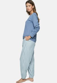 Un haut bleu clair à manches longues associé à un pantalon de pyjama rayé bleu clair et blanc. Le pantalon présente une taille élastique et des poignets fuselés.