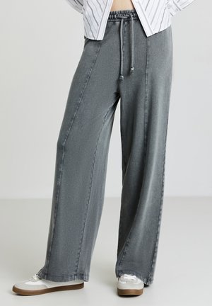 Pantaloni leggeri a gamba larga in denim grigio. Presentano una vita elastica con cordoncino e cuciture a contrasto. Abbinati a sneaker casual.