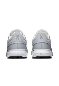 Graue Mesh-Sportschuhe mit einer glatten weißen Sohle, die ein minimalistisches Design und dezente Markenkennzeichnung an der Ferse aufweisen.