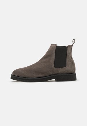 Stivale Chelsea grigio in suede con pannelli laterali elasticizzati, punta arrotondata e linguetta. Suola piatta in gomma nera. Design semplice ed elegante.