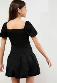Schwarzes Kleid mit Puffärmeln, strukturiertem Oberteil und gerafftem Rock. Viereckiger Rücken-Ausschnitt. Weicher Stoff, leicht und locker sitzendes Design.