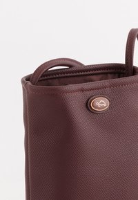 Maroonská kabelka z faux kůže s texturovaným povrchem, zaoblenými uchy a zlatým akcentovým knoflíkem s designem želvy.