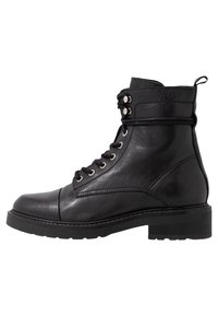 Botín negro de cuero hasta el tobillo con punta redonda, cordones en la parte frontal, ojales de metal y suela de goma resistente. Textura suave con acentos mínimos.