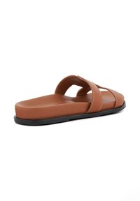 Brown synthetic flat slide sandal featuring two crossed straps and a textured footbed, with a black rubber sole and white stitching detail.