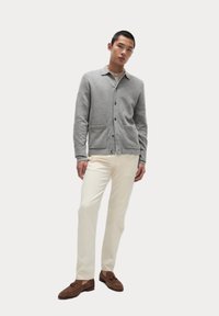 Grå uld cardigan med krave, med knapper og to frontlommer. Sammen med cremede bukser og brune ruskinds loafers.