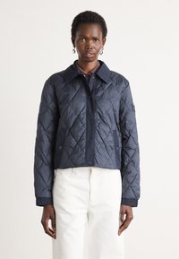 Marine blauwe gequilted jas met een knoopsluiting, grote kraag en geribbelde manchetten. Beschikt over een ruitpatroon en een slim fit ontwerp.