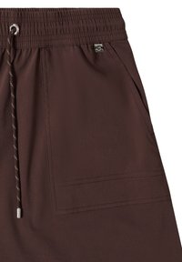 Short marron avec taille élastique, poche avant visible, et cordon marron avec embouts métalliques et œillet.