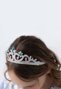 Silver tiara with intricate swirls, adorned with blue and clear gemstones, featuring a glittery texture. Positioned on dark, curly hair.