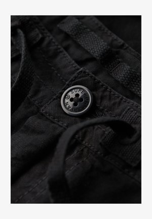 Black fabric with a textured finish, featuring a black button embossed with "Superdry" and a drawstring detail.