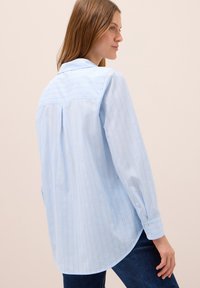 Camicia a righe blu chiaro con maniche lunghe, polsini con bottoni, orlo arrotondato e dettaglio piega sulla schiena, realizzata in un tessuto morbido.
