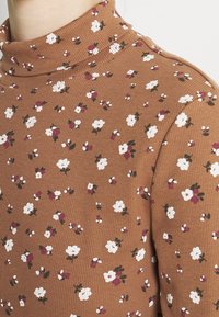 Braun gestreiftes Turtleneck-Oberteil mit kleinem weißen und burgunderfarbenem Blumenmuster, das eine taillierte Silhouette und strukturiertes Material aufweist.