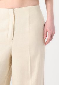 Beige linbukser med en glat tekstur, med en struktureret talje og en sidelomme.