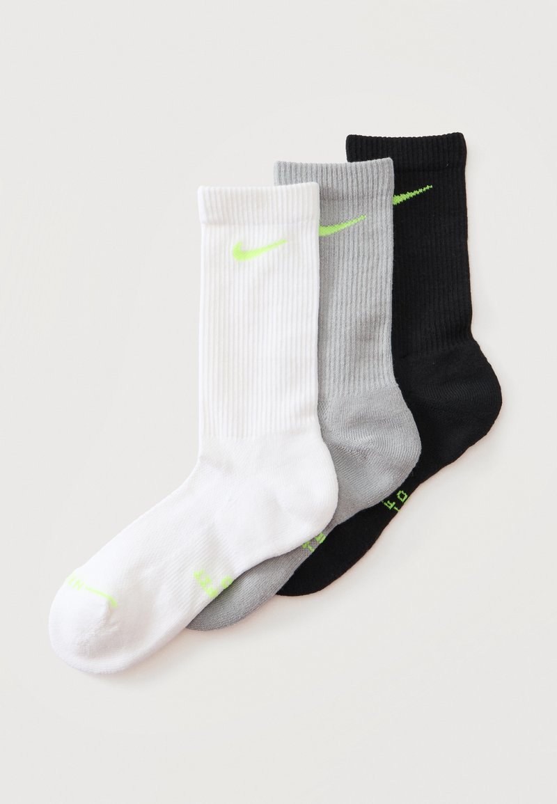 Τρεις κάλτσες Nike crew σε λευκό, γκρι και μαύρο με λογότυπο και κείμενο σε νέον πράσινο, τοποθετημένες επικαλυπτόμενες σε ανοιχτό φόντο.