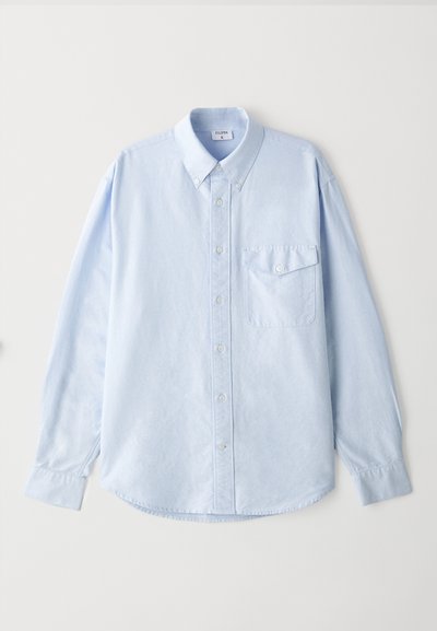 Lyseblå skjorte med knapp, laget av myk kvalitet, med klassisk krage, lange ermer og en brystlomme med klaff.