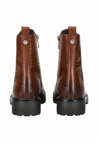 Par de botas de cuero marrón con textura de cocodrilo y suelas negras gruesas, mostradas desde atrás, con tiradores y cremalleras laterales.