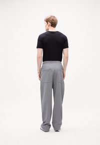 Gray sweatpants with a loose fit and elastic waistband, featuring two back pockets, paired with a black short-sleeve t-shirt.