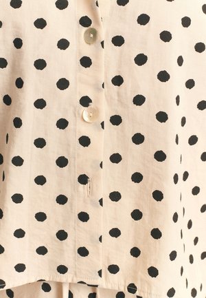 Lichtbeige overhemd met zwarte stippen. Voorzien van ronde knopen en een licht gestructureerde afwerking.