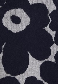 Neulottu villapaitakangas, jossa on suuriin, tummansinisiin kukkiin perustuva kuvio vaaleanharmaalla taustalla ja pehmeä, teksturoitu pinta.