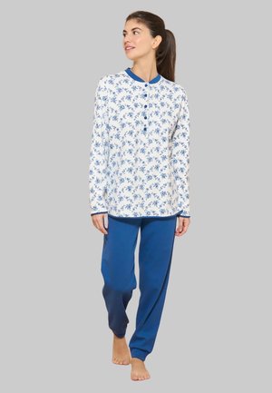 Top a manica lunga a fiori blu con base bianca, dotato di chiusura a bottoni. Abbinato a pantaloni da pigiama larghi di colore blu uniforme.