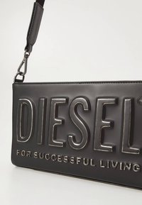 Black faux leather shoulder bag featuring a raised "DIESEL" logo, silver accents, and a detachable strap. Smooth texture with a rectangular shape.
