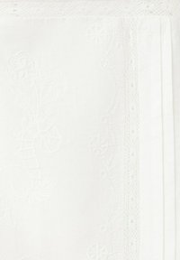 Tissu blanc avec une délicate broderie florale et une bordure en dentelle le long du bord, plié soigneusement.