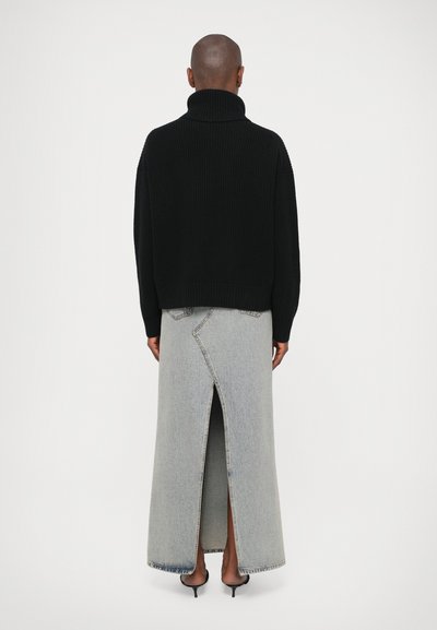 Must mustrikkiga must turtleneck-sweater, millele on juurde sobitatud pikk hall denim-seelik, mis omab kõrget lõhet ja vastandlike õmblusdetailidega.