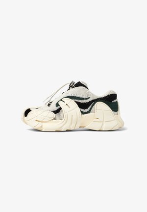 Zapatillas de punto en color crema con patrones de olas verdes y negras, que cuentan con un diseño de punta único, un sistema de cordones ajustable y una suela texturizada.