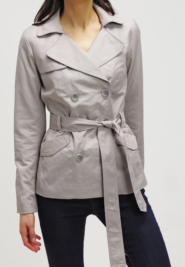 Trench coat gris claro, de doble pecho, con cinturón de lazo, que presenta dos bolsillos frontales, cuello con muesca y una tela suave y texturizada.