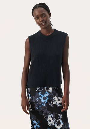 Zwarte mouwloze gebreide top met een ronde hals, met een zachte textuur. Gecombineerd met een bloemenpatroon rok in blauw en zwart tinten.