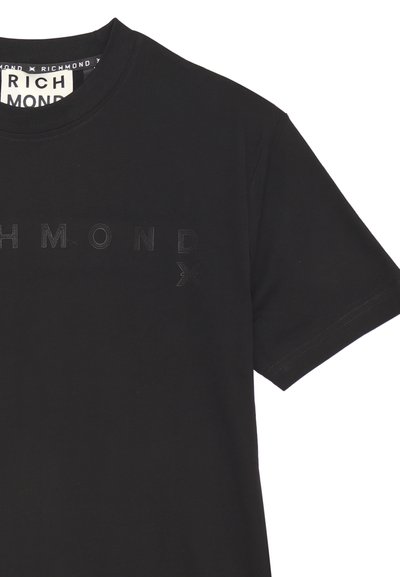 T-shirt in cotone nero con scollatura rotonda e maniche corte. Presenta un logo in rilievo e testurizzato sulla parte anteriore in un colore a contrasto.