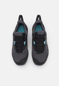 Scarpe sportive grigie da uomo con accenti neri, parte superiore in rete, design con lacci, soletta teal e linguette sul tallone.