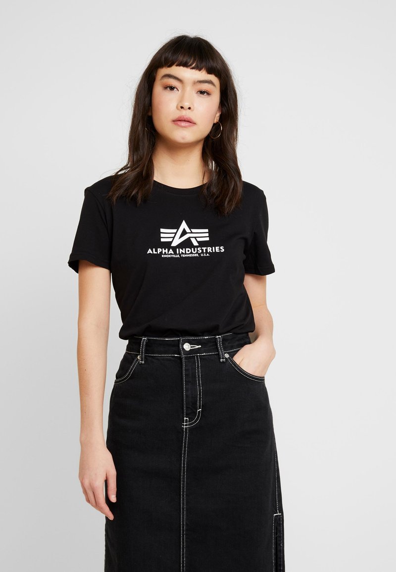 T-shirt en coton noir avec le logo « Alpha Industries » blanc, associé à une jupe en denim noir taille haute avec des coutures contrastantes et une fente à l'avant.