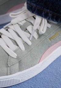Hele roheline nubukist sneaker valgete paelte ja detailidega, millel on roosa küljeriba ja tekstureeritud valge kummitald.