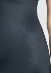 Form-fitting dark gray dress made of textured, stretchy fabric. Features ribbed patterns and a smooth silhouette. No visible hardware or accents.