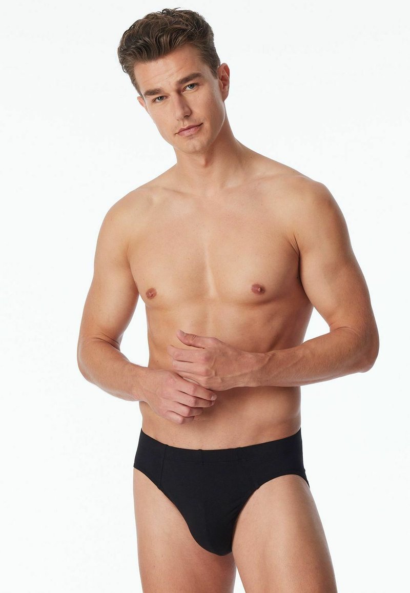 Schwarze Baumwollslips mit enganliegendem Sitz, die eine glatte Oberfläche und ein minimalistisches Design aufweisen. Keine sichtbaren Logos oder Muster.