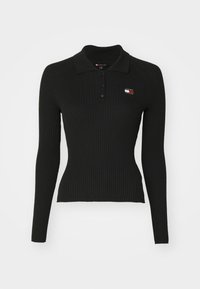 Polo de manga larga negro con textura de costillas y cuello con solapa, que presenta un pequeño parche de logo en el pecho y una silueta ajustada.