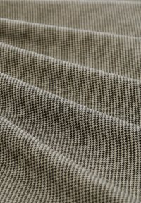 Tkanina iz preje s vzorcem houndstooth v črno-rjavi barvi. Teksturirana površina z izrazitimi črtami, ki prikazuje globino in dimenzijo.